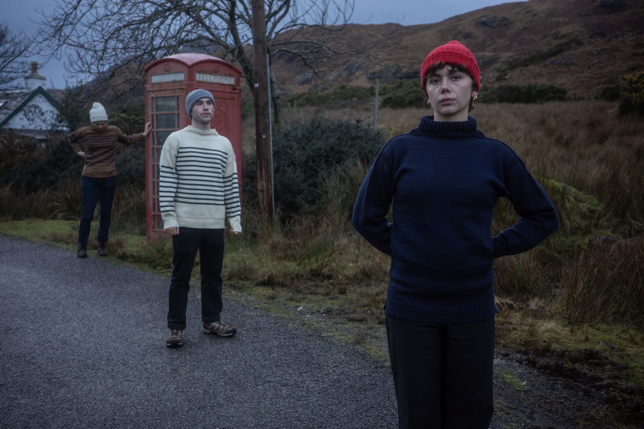 male and female models wearing traditional Guernsey jumpers by a telephone box in the country